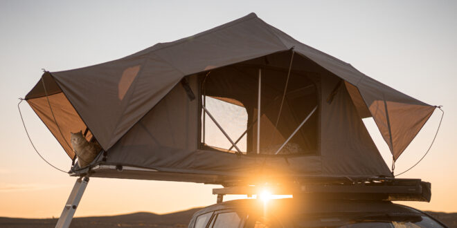 Ein Autodachzelt zum Campen auf dem Dachträger eines Geländewagens in der Wüste bei Sonnenuntergang